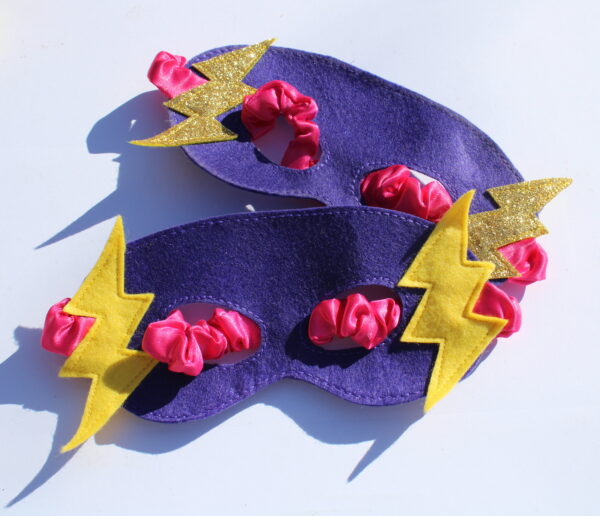 purple felt superhero eye mask with gold and yellow lightning bolts and pink elasticated strap